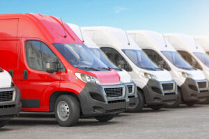A fleet of white work vans, with one red van pulling forward