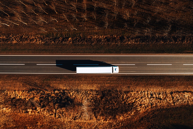 Freight transportation and logistics from above, drone photography of truck on the road through plain countryside landscape